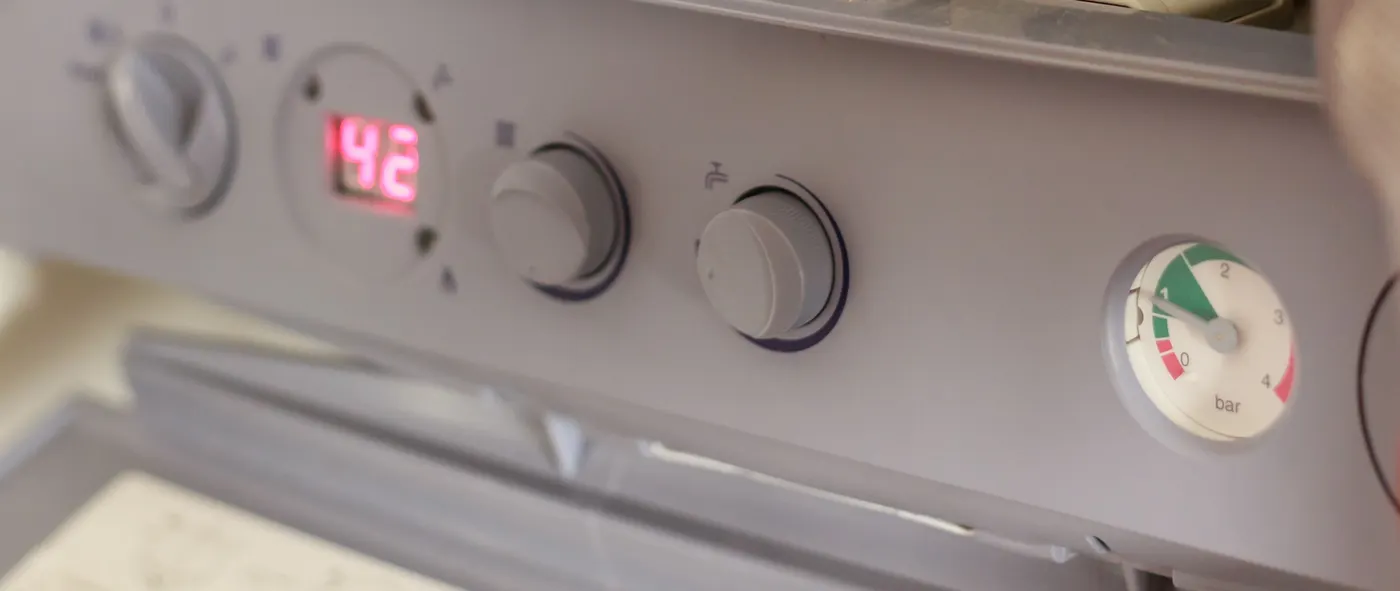 Boiler control panel with a digital temperature display and a round pressure gauge with a green safe zone and red low and high zones, marked in bar