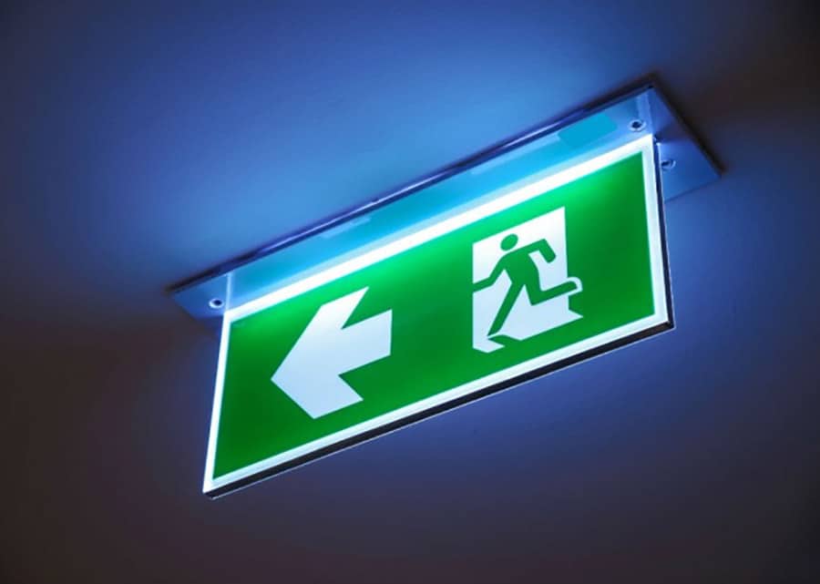 Emergency lighting bulkhead luminaire illuminated during a BS 5266 3-hour discharge test in a London commercial building